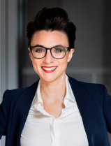 Christine Antlanger-Winter lächelt freundlich mit offenem Mund in die Kamera. Sie trägt eine weiße Bluse unter einem dunkelblauem Blazer und eine große Brille.