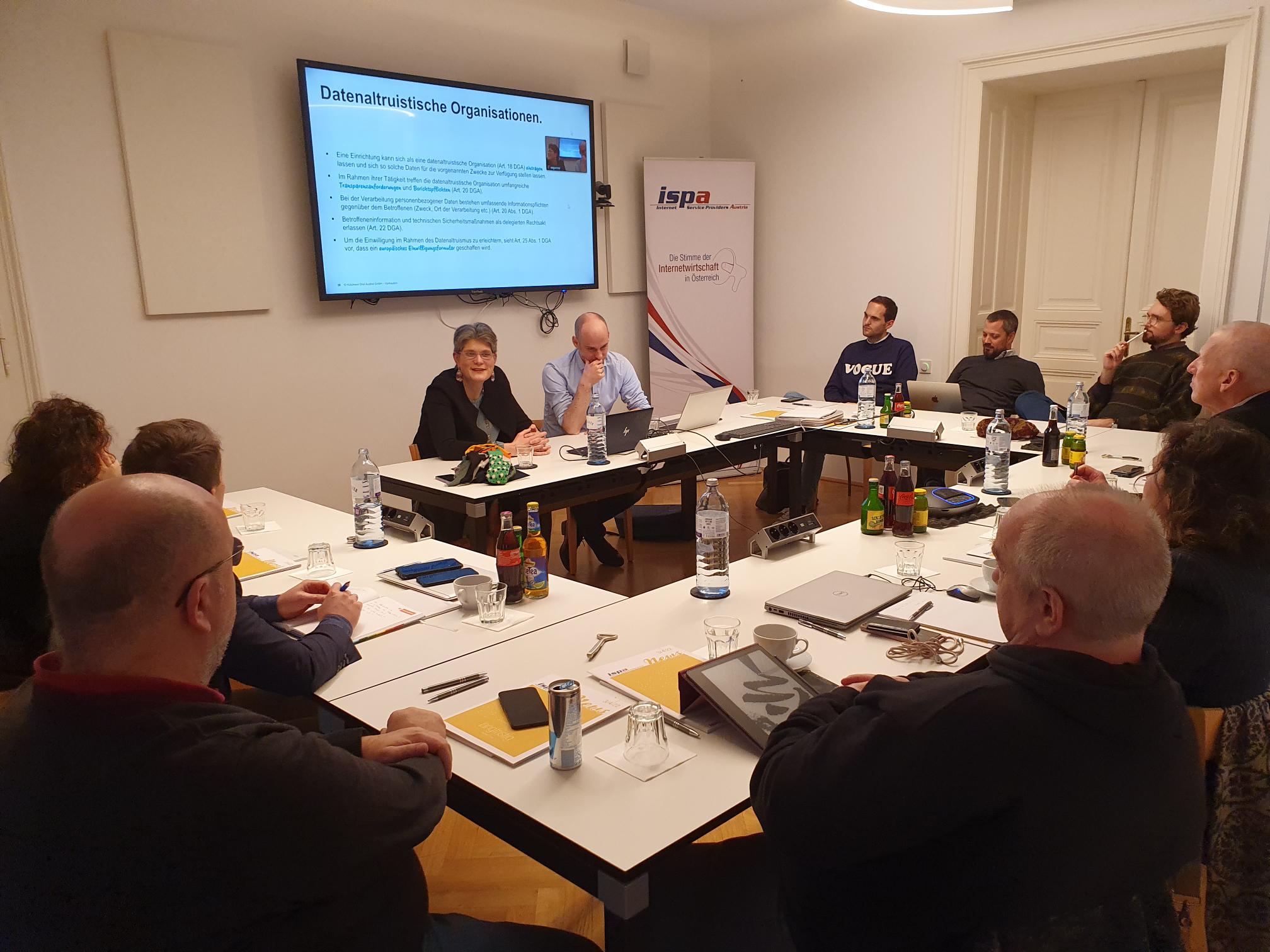 Foto von der Veranstaltung, die Vortragenden Natalie Segúr-Cabanac und Jürgen Bauer präsentieren, das Publikum lauscht interessiert.